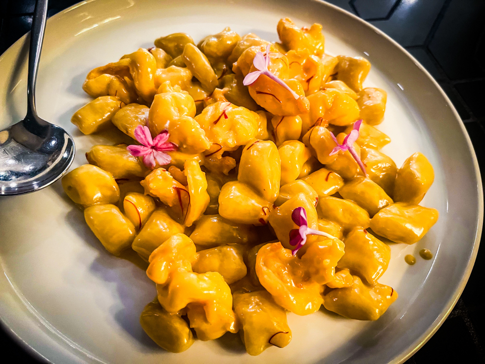 Gnocchi with saffron and shrimp served on a plate, featuring golden saffron-infused gnocchi and tender shrimp, garnished with herbs.