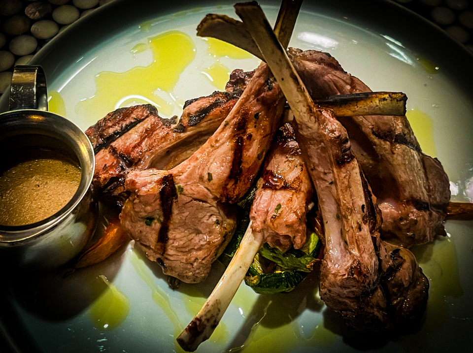 Grilled Lamb Chops (Agnello Scottadito) served with a charred, crispy exterior, garnished with herbs and lemon wedges on a rustic plate.