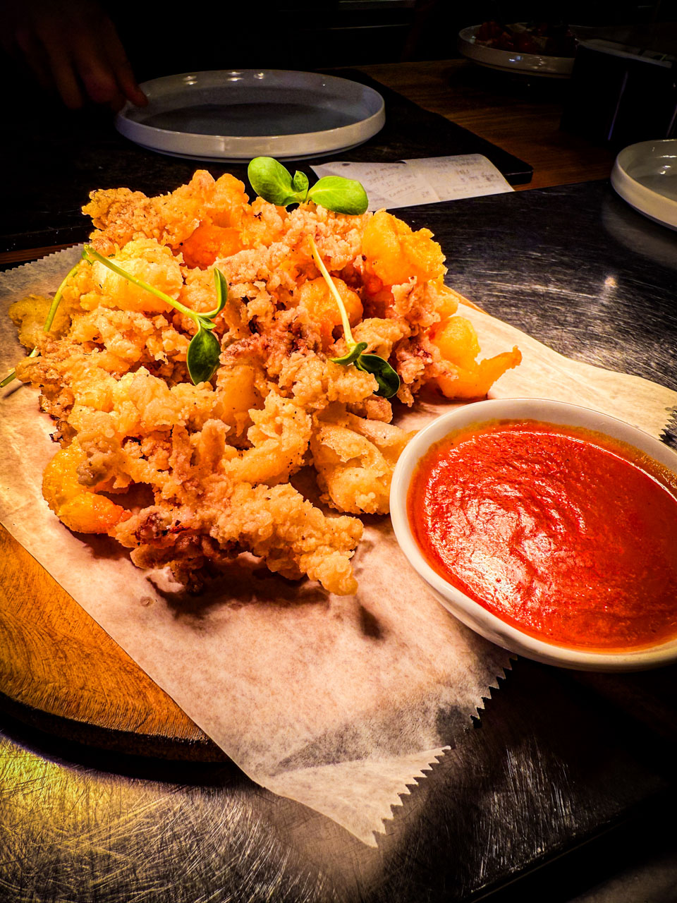 Crispy calamari served on a plate, golden and lightly breaded, with a side of dipping sauce and lemon wedges for garnish.