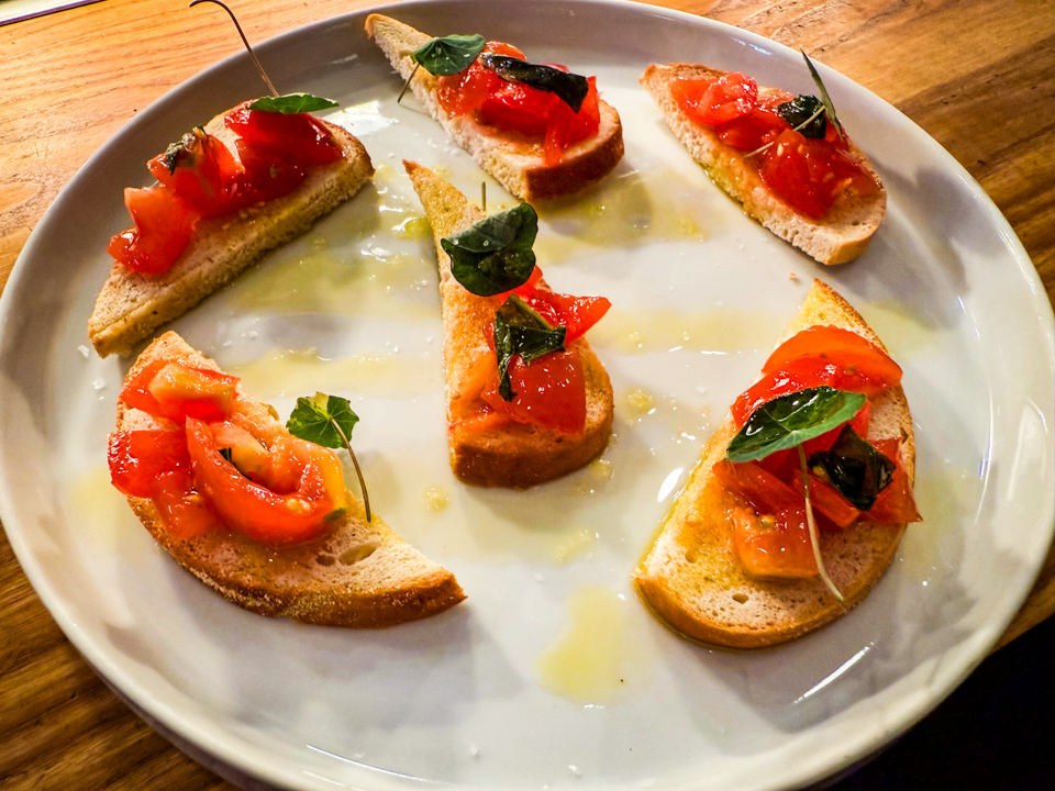 Bruschetta topped with fresh diced tomatoes, garlic, basil, and a drizzle of olive oil on crispy toasted bread slices. Classic Italian appetizer.