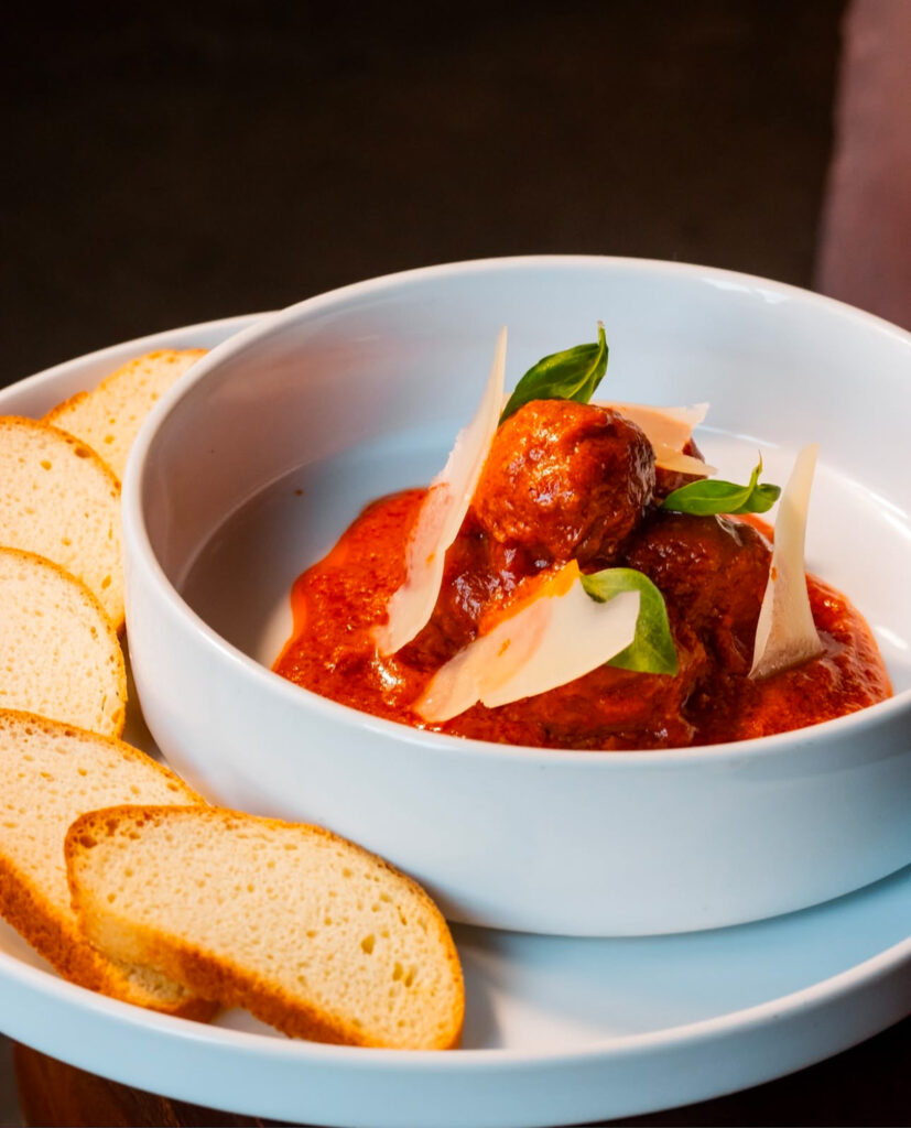 Plate of authentic Italian meatballs topped with fresh basil and Parmesan, served in a rich tomato sauce at Dante, the best Italian restaurant in Houston